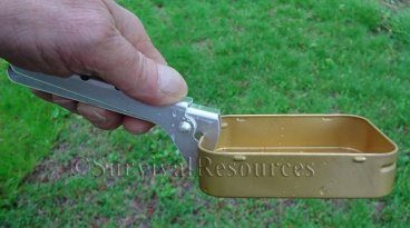 Shown holding large survival tin.
